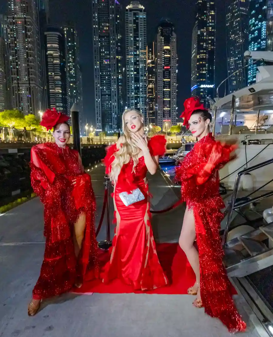 Three stylish women stand at the marina, ready to embark on a yacht cruise in Dubai.
