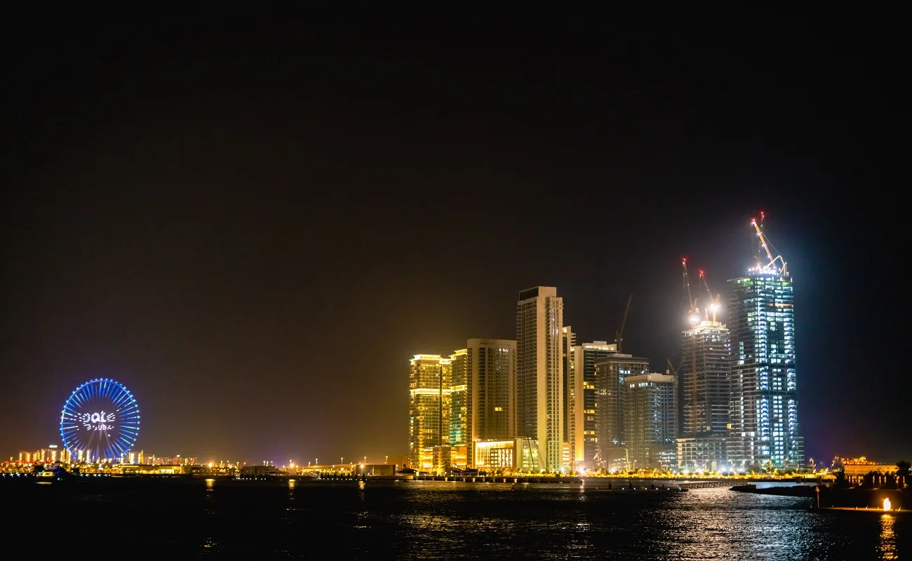 A tranquil boat dinner cruise in Dubai, showcasing the city's dazzling skyline and the famous Ain wheel against the night backdrop.