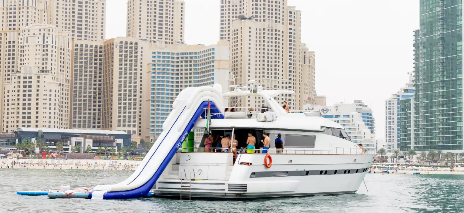 a luxury shared yacht with waterslide sails near dubai city skyline for dubai yacht cruise